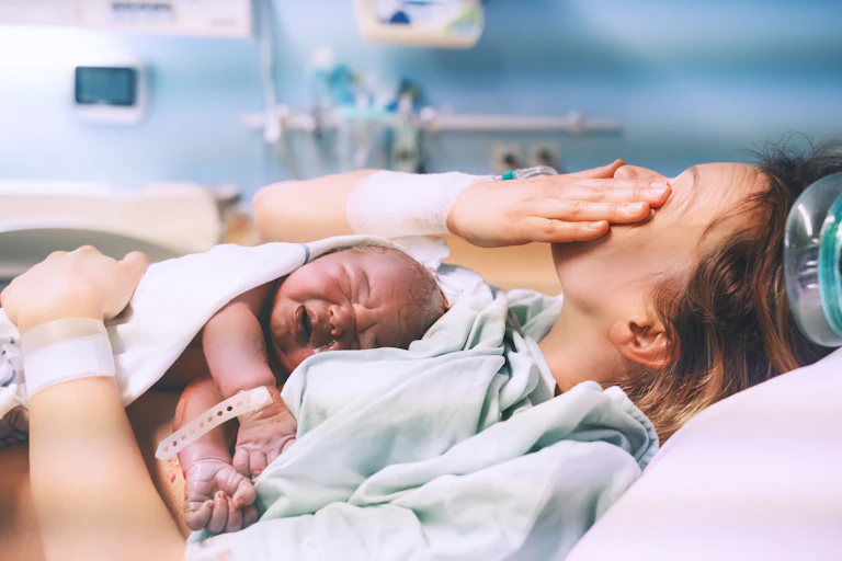 woman in hospital with newborn on chest