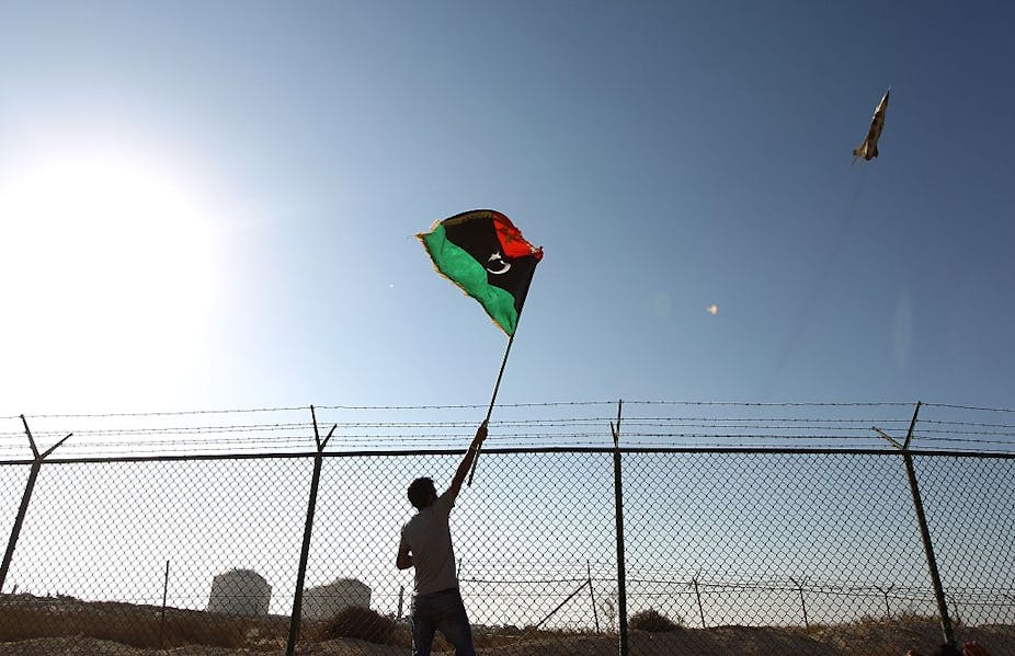 A man waves a Libyan flag as a fighter jet flies by Zueitina oil terminal in 2016. Abdullah Doma/AFP via Getty Images A man waves a Libyan flag