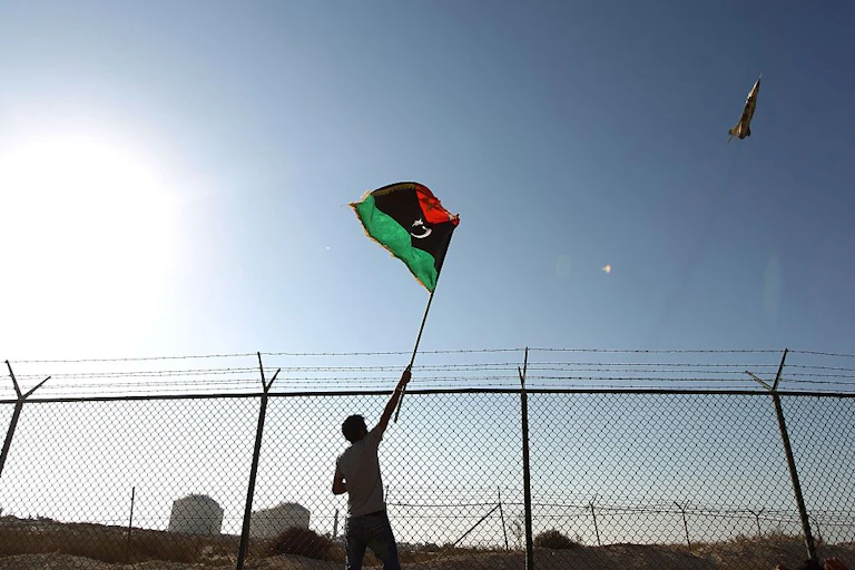 A man waves a Libyan flag as a fighter jet flies by Zueitina oil terminal in 2016. Abdullah Doma/AFP via Getty Images A man waves a Libyan flag