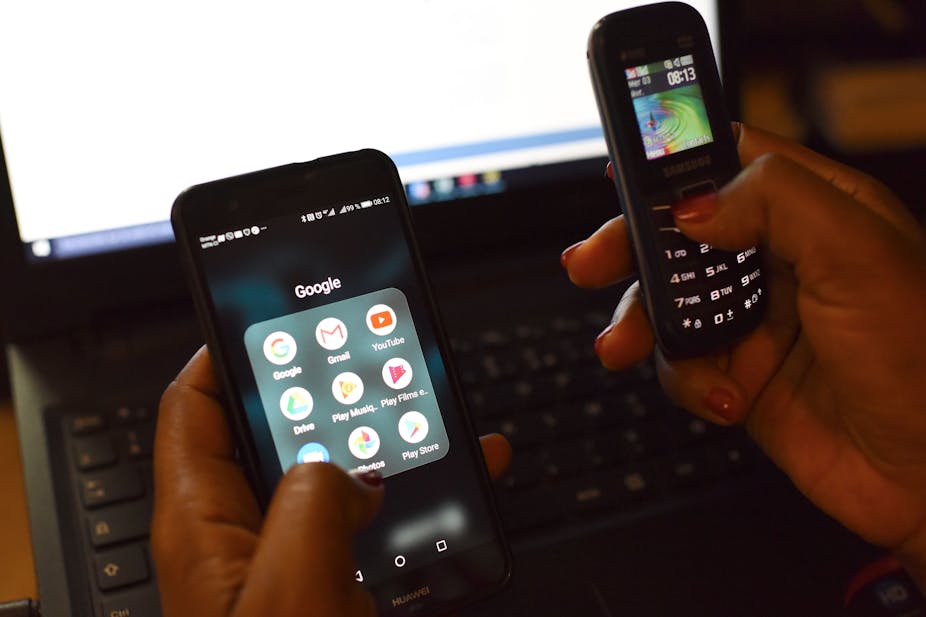 A woman uses a smartphone and a mobilephone in front of a laptop on April 3, 2019, in Abidjan