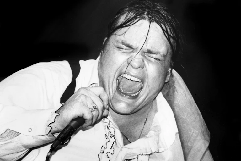 Sweaty man screams into microphone.