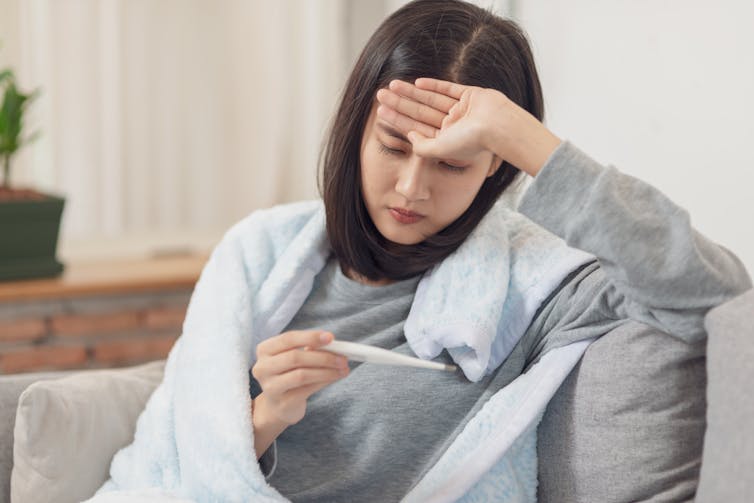 A woman with fever checking her temperature