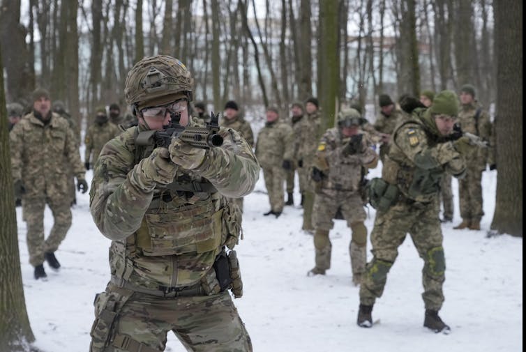 People in combat gear carrying weapons in a snowy park.