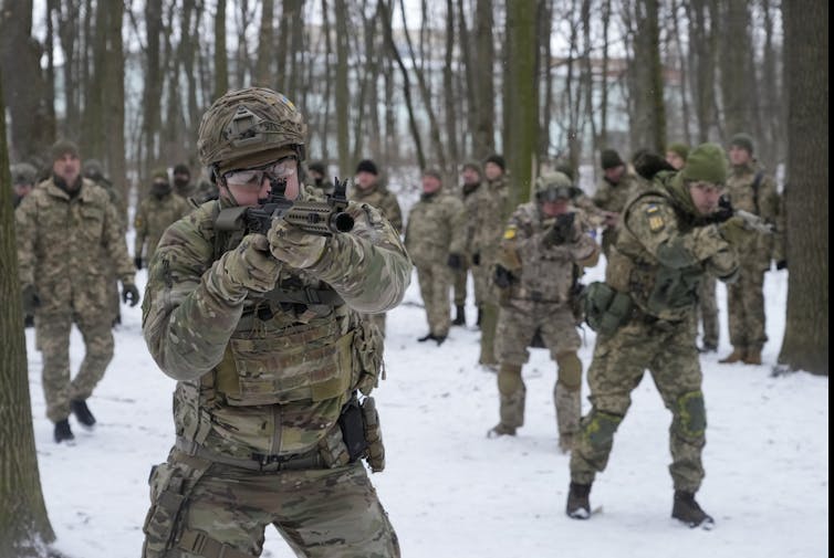 People in combat gear carrying weapons in a snowy park.