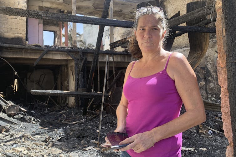Une femme debout devant une maison détruite
