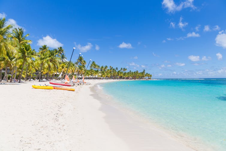 Des bateaux sur une plage, au bord d’une mer turquoise