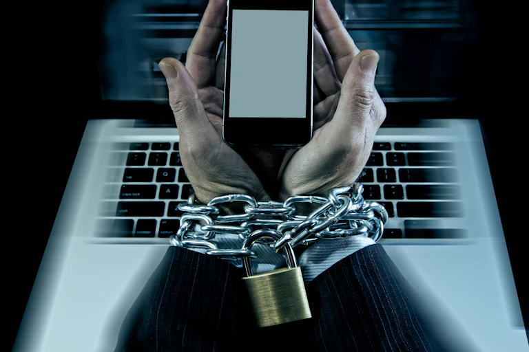manos de hombre trajeado encadenadas a ordenador portátil y teléfono móviñ.
