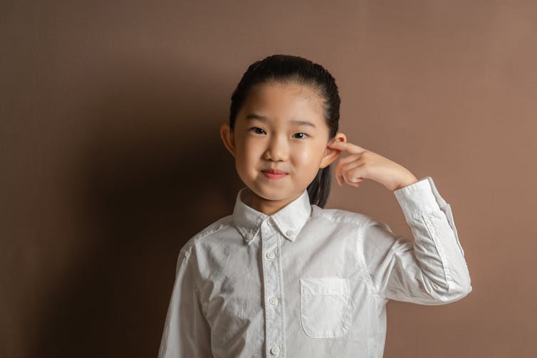 little girl poking her finger in her ear