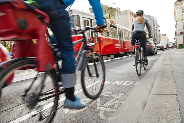 Cyclists riding along a bike path next to traffic in Vienna.