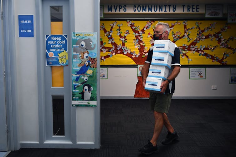 man carries boxes of rapid tests into school