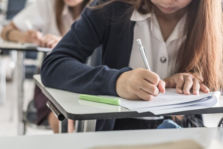 Girl writing test at desk.