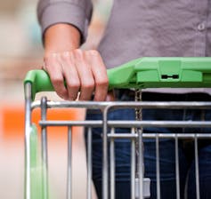 Top of shopping trolley with woman's hand on it.