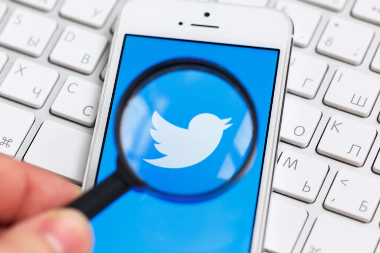 Lupa sobre logotipo de twitter en teléfono móvil.