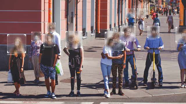 A group of people standing at a crosswalk with their faces blurred and a digital id typed underneath