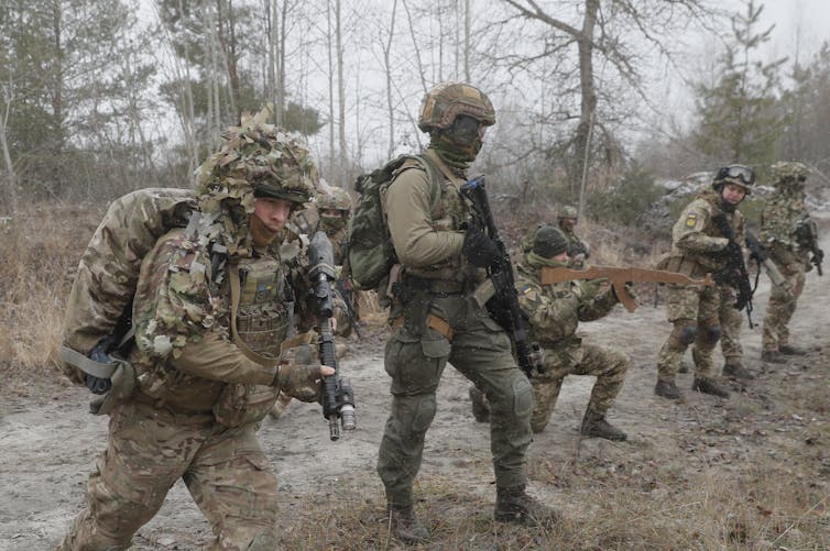 Soliders in combat gear holding guns.