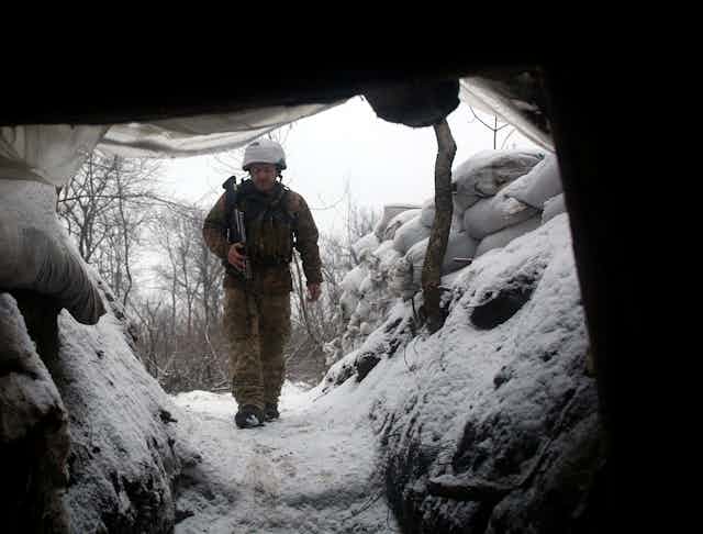 A Ukrainian soldier walks along a trench.
