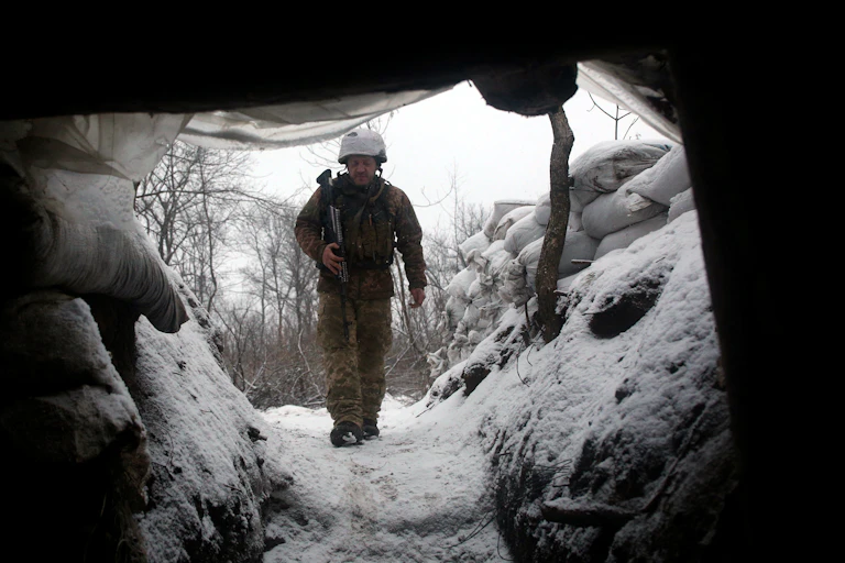 A Ukrainian soldier walks along a trench.