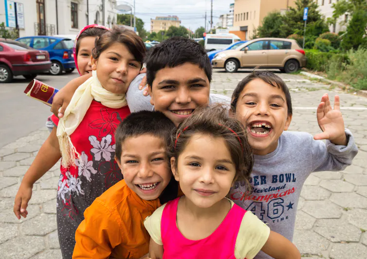 A group of young children smile up at the camera