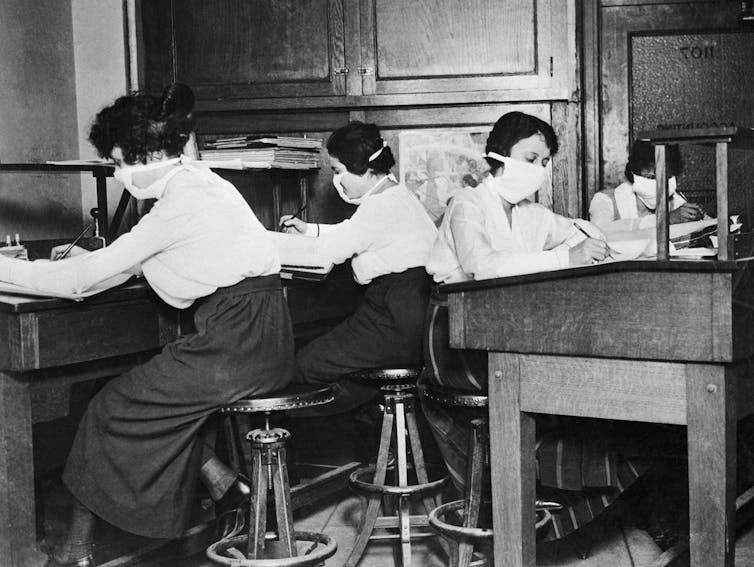 masked clerks at desks in early 20th century