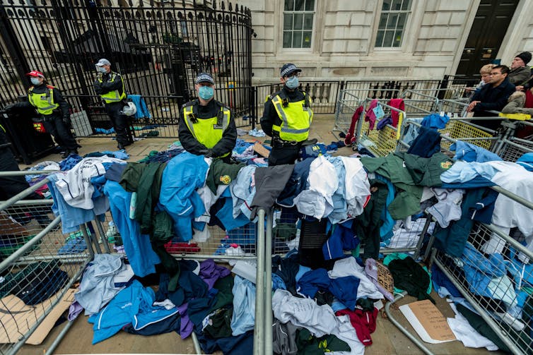 Clothes piled on railings with police stood behind.