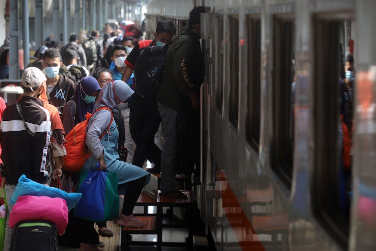 Travelers on a platform waiting to climb into a train.