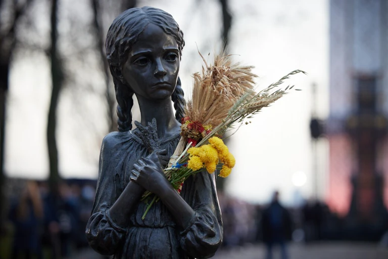A statue of a girl during the Ukrainian famine, in which someone has placed wheat and flowers.