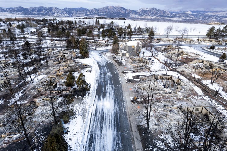 An aerial view of a neighborhood mostly reduced to rubble with the exception of one home