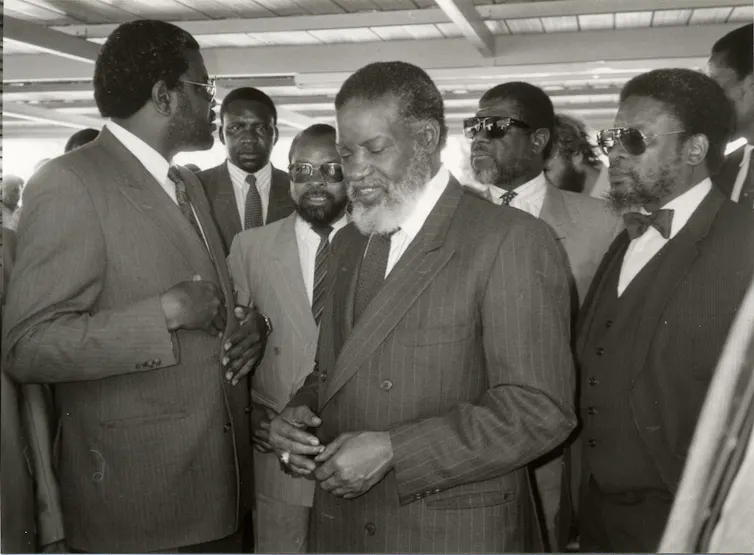A group of men stand on their feet wearing suits and ties.