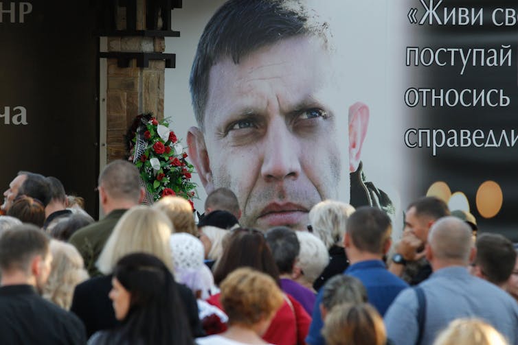 People gather round a poster of the former chief of the self-proclaimed Donetsk People's Republic, Alexander Zakharchenko.