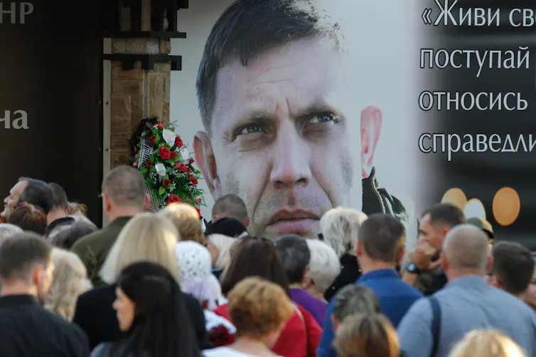 People gather round a poster of the former chief of the self-proclaimed Donetsk People's Republic, Alexander Zakharchenko.