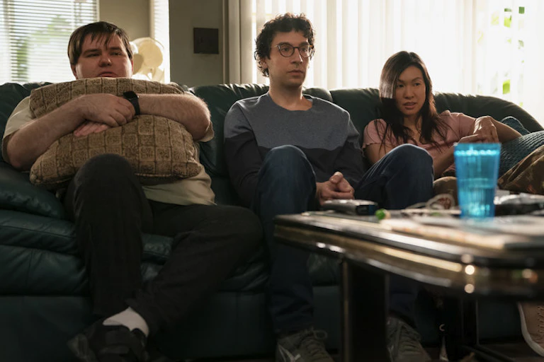 Three people sit on a sofa.