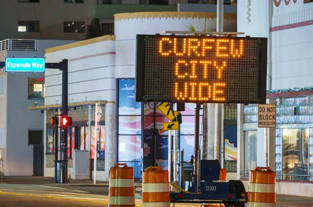 A sign on an empty street saying: curfew city wide.