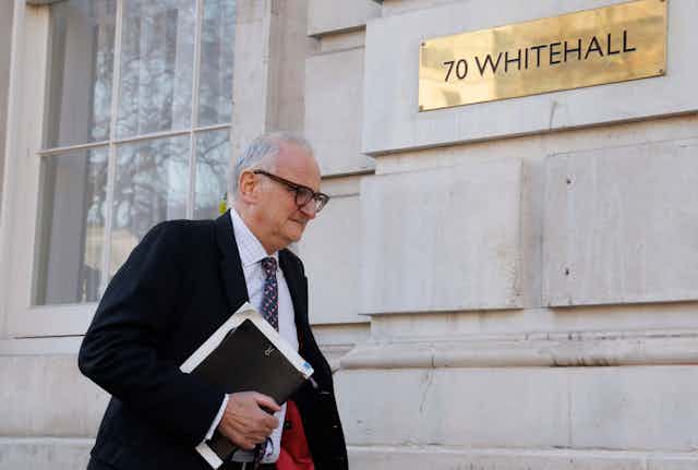 Lord Agnew walks by a Whitehall building while holding a folder under his arm