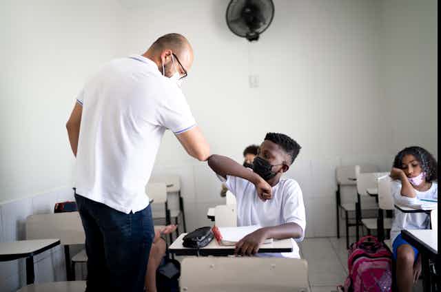 A Black man leads a therapy session in a classroom.