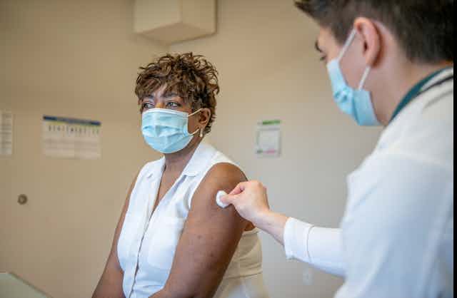 A doctor prepares to give a booster shot to a senior woman.
