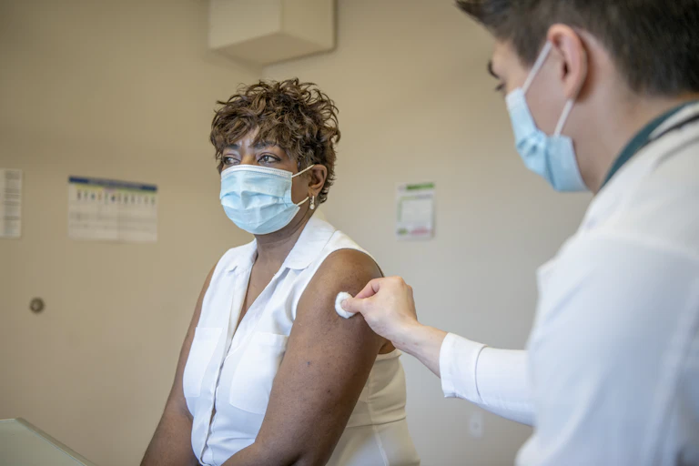 A doctor prepares to give a booster shot to a senior woman.