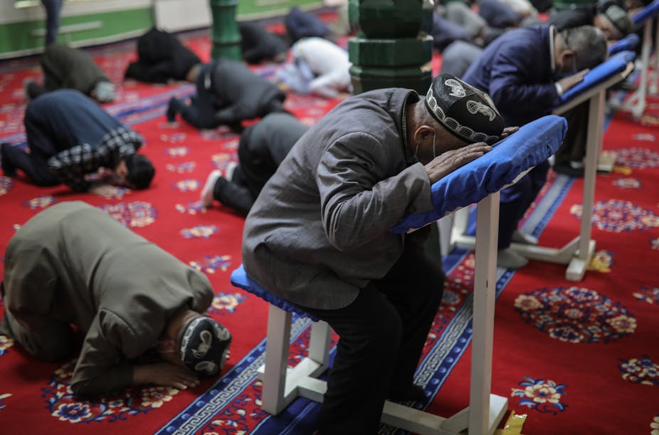 Men bending down to pray at a mosque. 