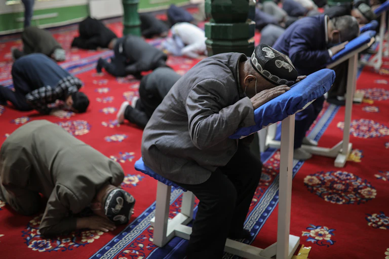 Men bending down to pray at a mosque.
