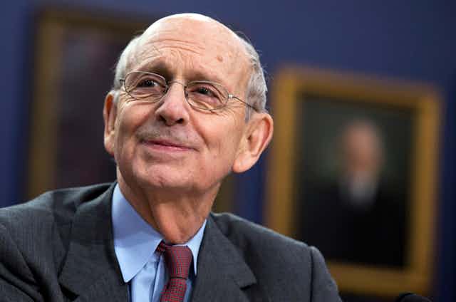 Supreme Court Associate Justice Stephen Breyer smiles as he looks off into the distance.