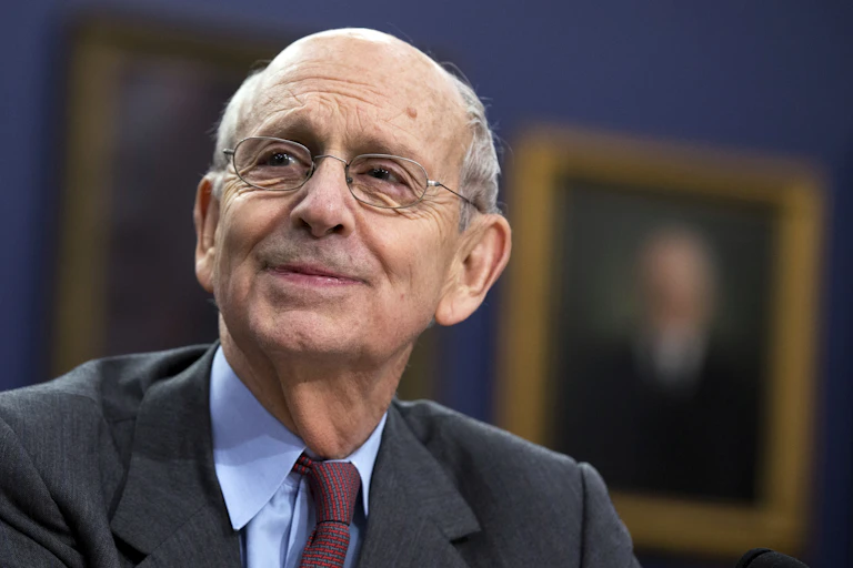 Supreme Court Associate Justice Stephen Breyer smiles as he looks off into the distance.