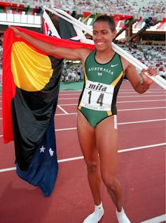 Cathy Freeman carrying the Aboriginal flag.