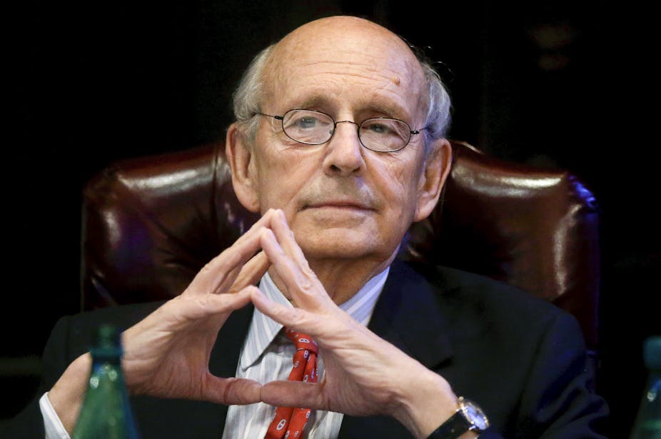 Supreme Court Justice Stephen Breyer sits on a leather chair with his hands together.