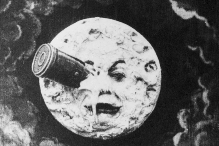 A black and white drawing of a rocket crashed into a fanciful face in the moon.