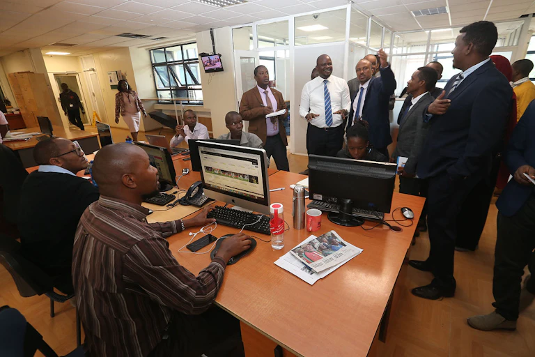 Men in a room filled with journalists having a discussion