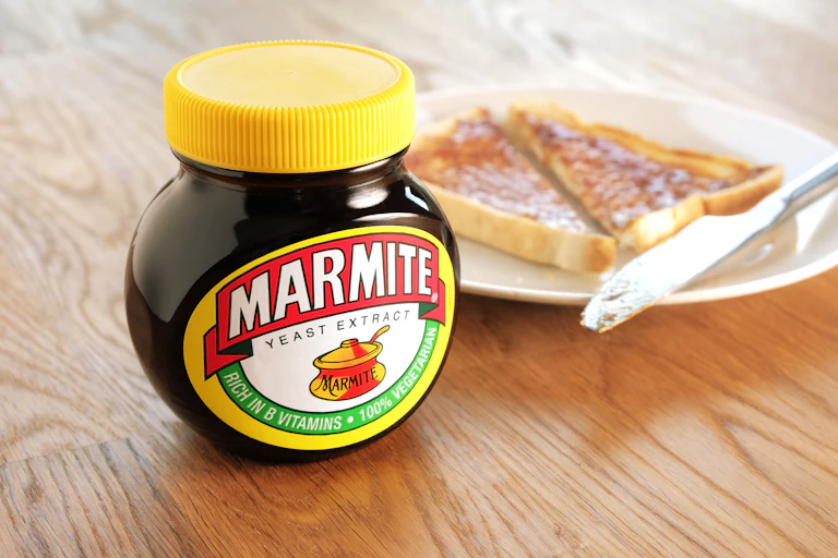Jar of Marmite next to plate of toast.