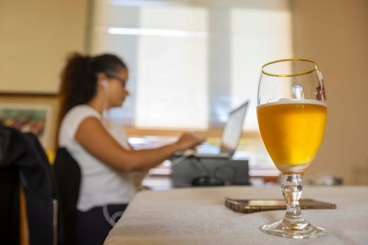 Woman working at a word processor with a glass of beer in the foreground