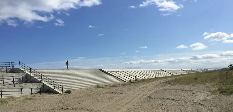 Man walks along concrete wall