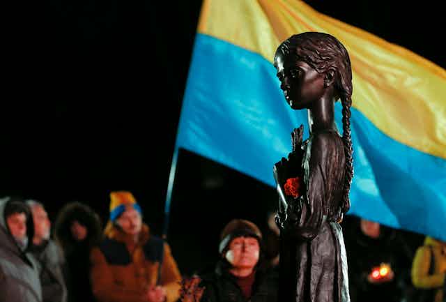 Ukrainians wave the national flag at a memorial to the 'Great Famine' of the 1930s