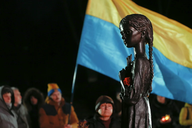 Ukrainians wave the national flag at a memorial to the 'Great Famine' of the 1930s