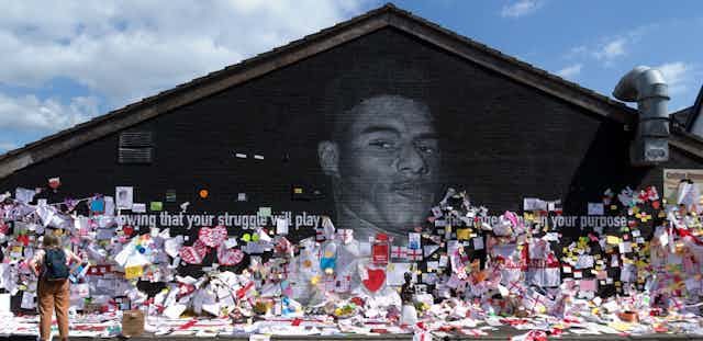Mural of Marcus Rashford covered with notes, pictures and flags. 